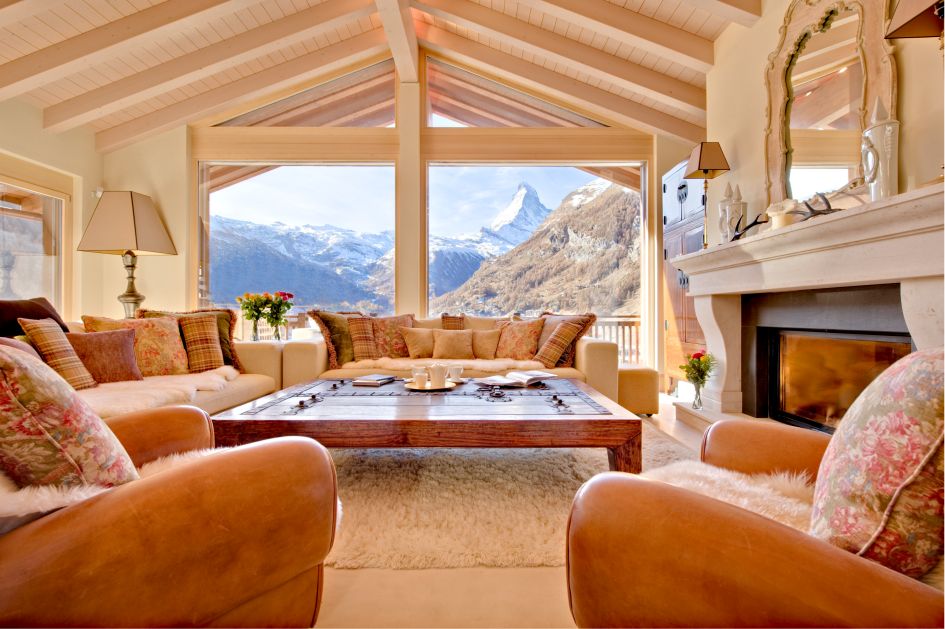 The living room of Chalet Grace, with Matterhorn views through the window in the background, a mut-have feature for any luxury chalet in Zermatt.