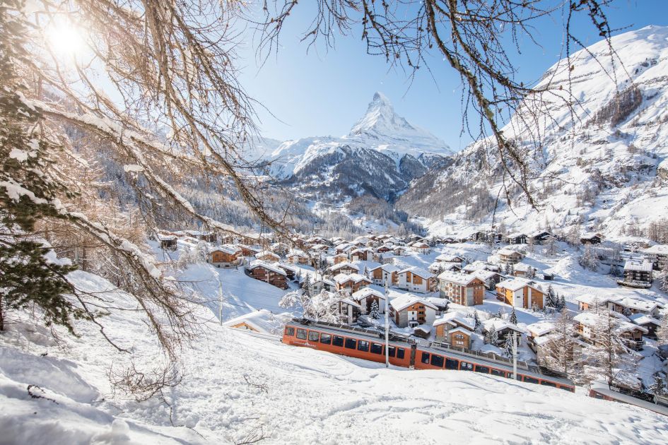 An image of Zermatt ski resort, with the Gornergrat Bahn in the foreground, a number of luxury accommodation in Zermatt, and then the Matterhorn in the background. 