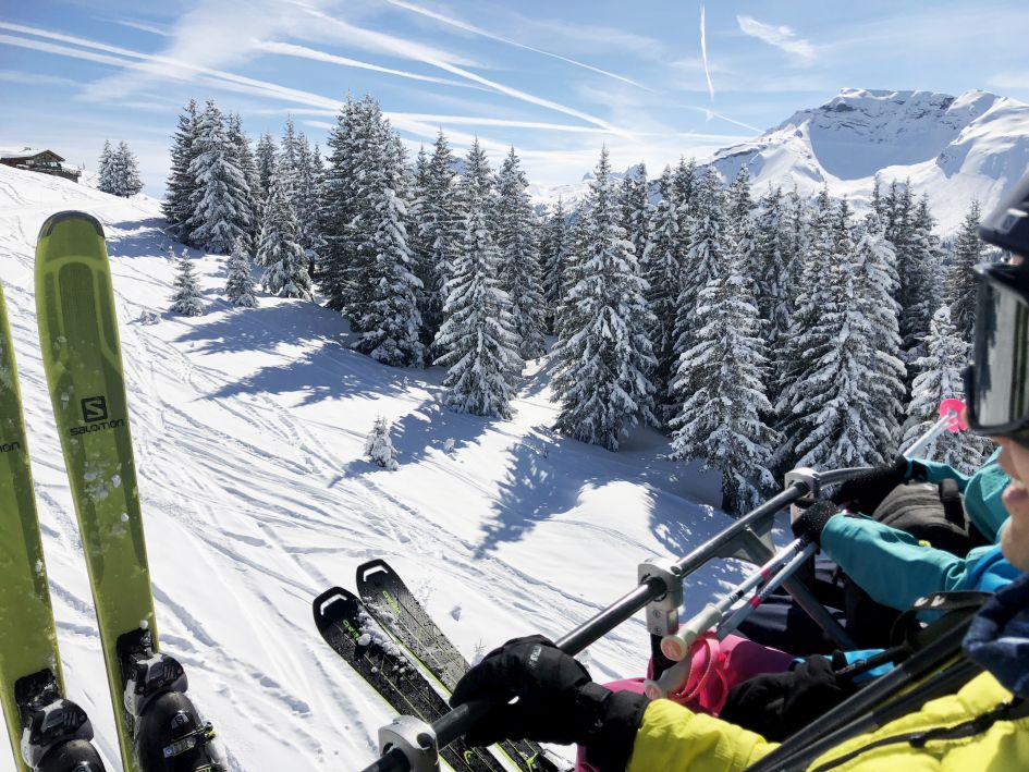 Group of skiers on a chairlift, looking our over the snow and piste below