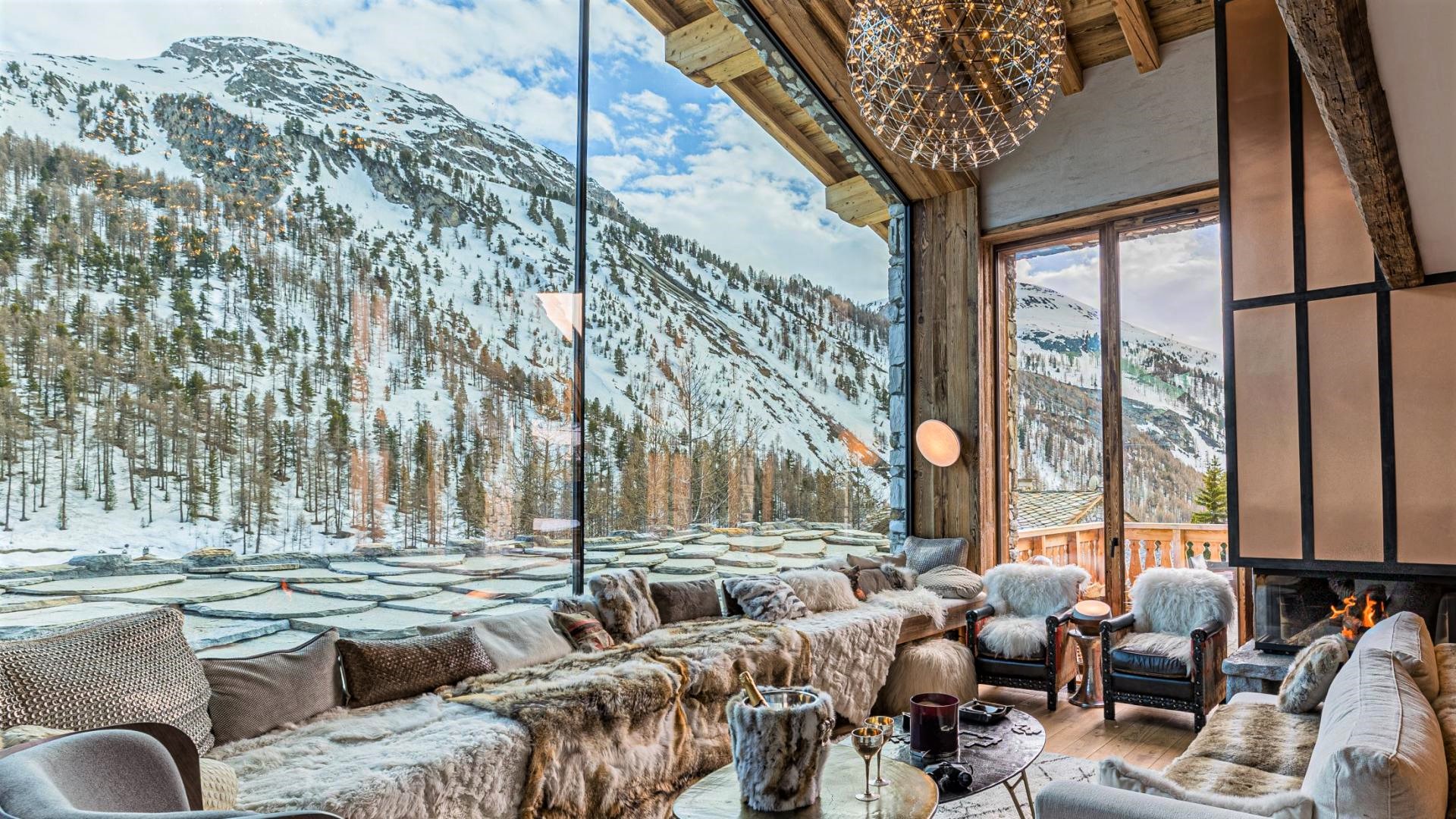 Image of the living room with large glass windows, framing the snowy mountain views.