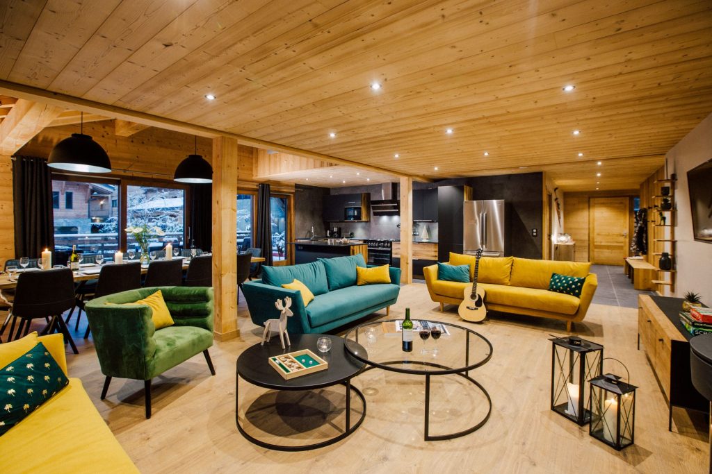 Large open-plan living room with stylish armchairs and guitar at chalet Harmonie, a luxury self catered ski chalet in Morzine
