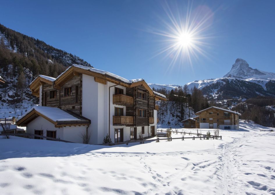 Chalet Elena exterior with blue skies and sunshine. With a Matterhorn view to complete the image, it is easy to see why this is a top self catered chalet in Zermatt