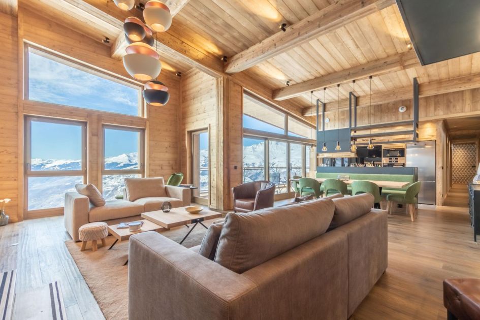 Dou Lodge's main open-plan living area features double-height ceilings, a minimalistic design and large windows capturing sensational mountain views - perfect for your luxury self catered ski holiday in the French Alps!