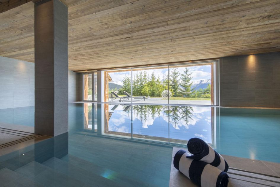 Chalet Teredo, Verbier Chalet Teredo is the perfect luxury ski chalet for New Year in Verbier, sleeping up to 10 guests. Featuring as one of our luxury chalets with an indoor swimming pool, we can see the incredible 12m long pool in this picture with floor to ceiling windows in the background looking out to the chalet's terrace and breathtaking views.