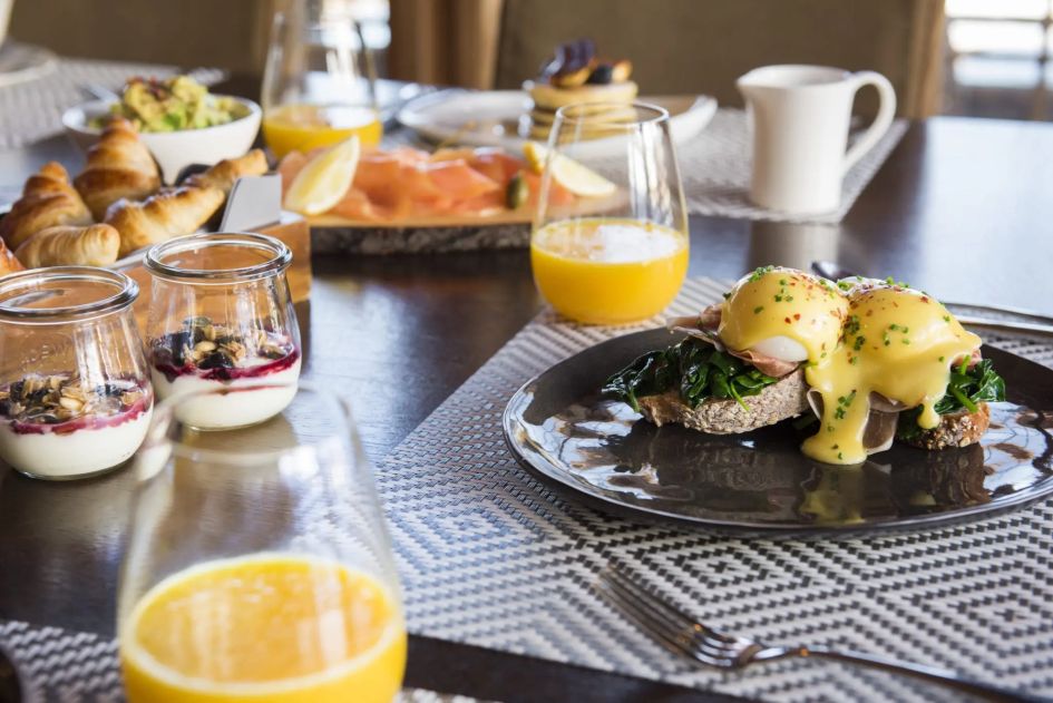 Breakfast on offer at a luxury catered ski chalet in Verbier, with an assortment of cooked and continental options, including eggs, croissants, salmon and pancakes, and juices.