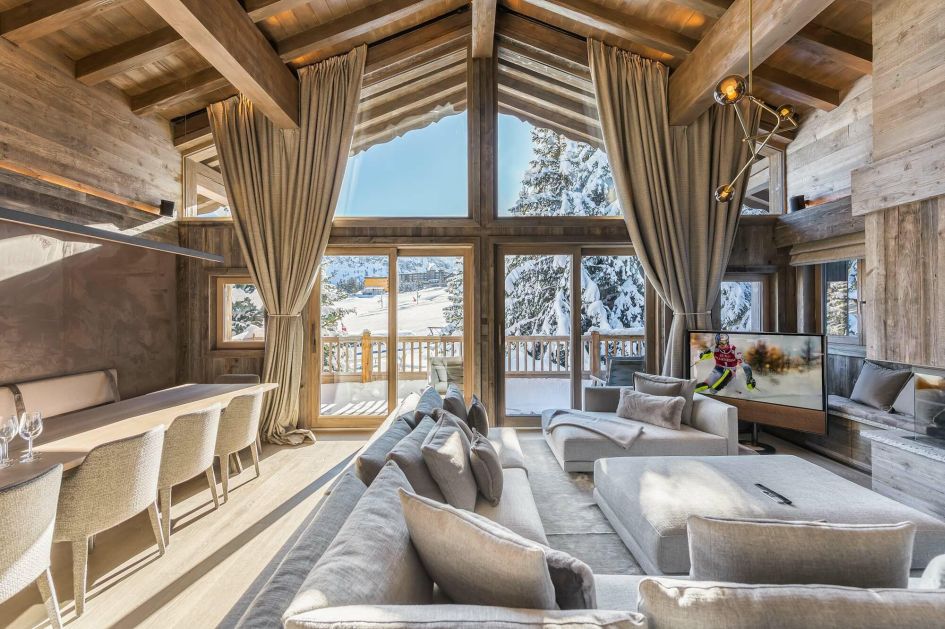 The lounge and dining area of Chalet Bellarossa, a ski in ski out chalet in Courchevel 1850, with an amazing view out towards the Pralong piste it sits adjacent to.