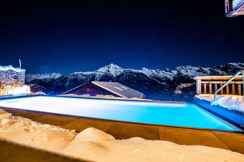 The swimming pool of Chalet V and the mountain views from it Views of the Rhone Valley in the distance, and the luxury heated outdoor swimming pool of Chalet V, a catered ski chalet in Verbier.