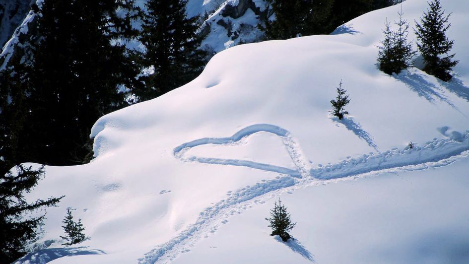A heart drawn into fresh powder on the mountain-side, a perfect romantic setting for a mountain proposal.