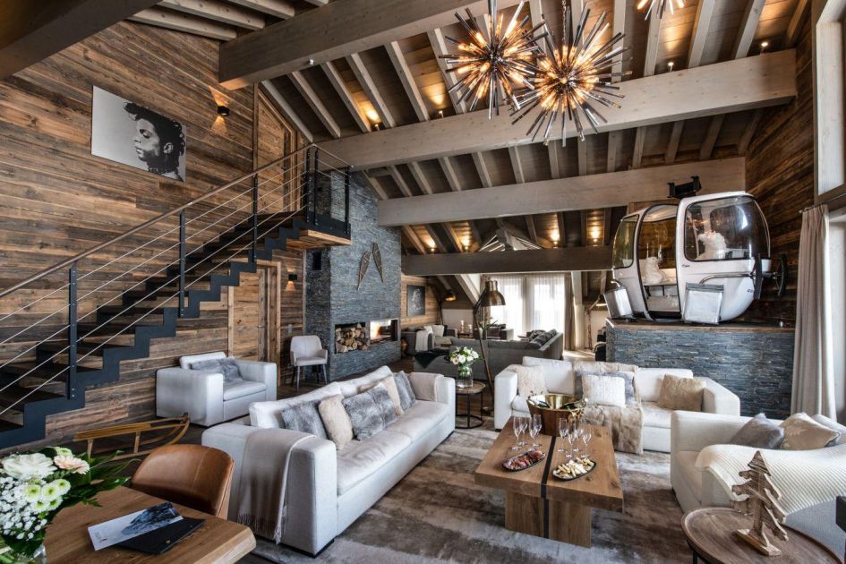 Interior of Mammoth Lodge Penthouse 1 with tall ceilings, a stone fireplace and a gondola lift car.  Featuring contemporary alpine decor, luxury ski apartments in mountain residences retain the typical ski chalet environment. 