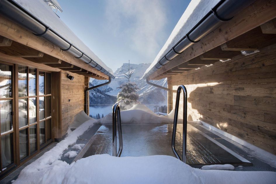 The outdoor hot tub at Chalet Mimi between the chalet walls with a stunning snowy view 