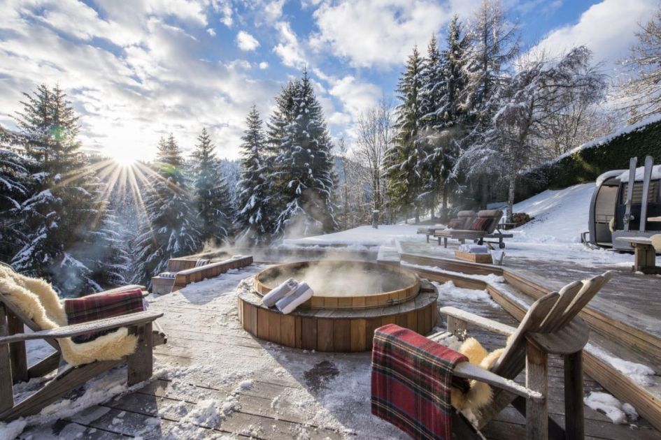 The forsty terrace at Ferme de Moudon, complete with an outdoor cedar wood hot tub and fleece blanket lined chairs. Snow covered trees complete the background for the ultimate winter escape. 