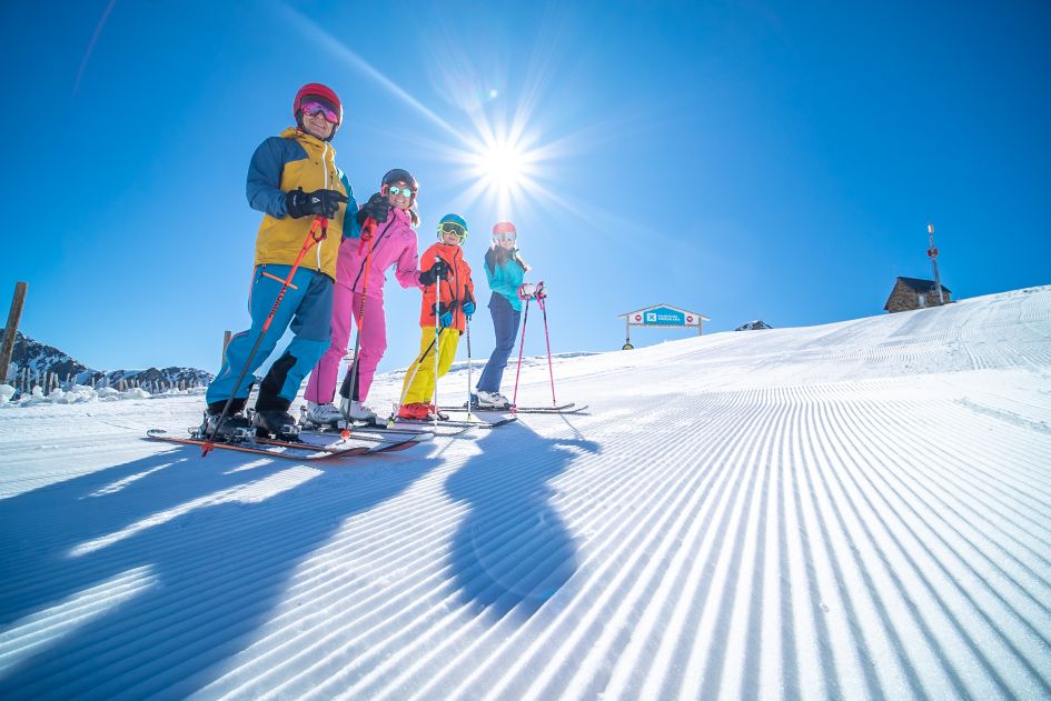 A family on the slopes on a sunny day in the Grandvalira ski area.