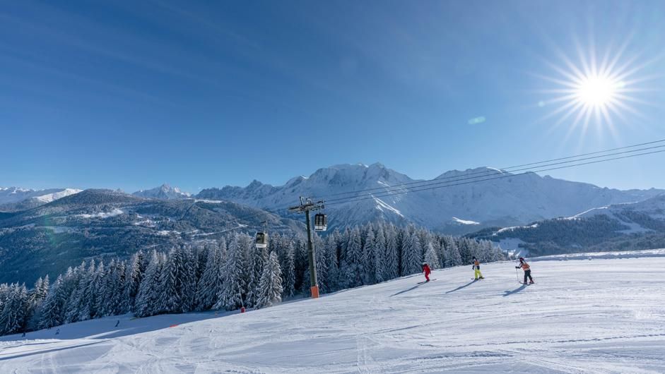 Blue skies and sunshine complementing stunning mountain views with three skiers skiing in Saint Gervais