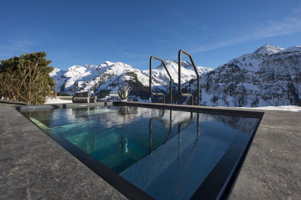 Hot tub of Chalet ÜberHaus overlooking the mountains, with champagne on the edge. Perfect for a day in the sun on a luxury catered ski holiday in Austria.