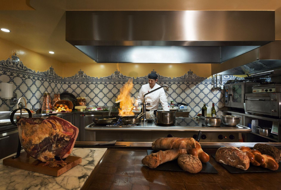 Kitchen at Truffe Blanche, Verbier Private chef at Chalet Truffe Blanche, with a flambé in action, cured meats and breads in the foreground.