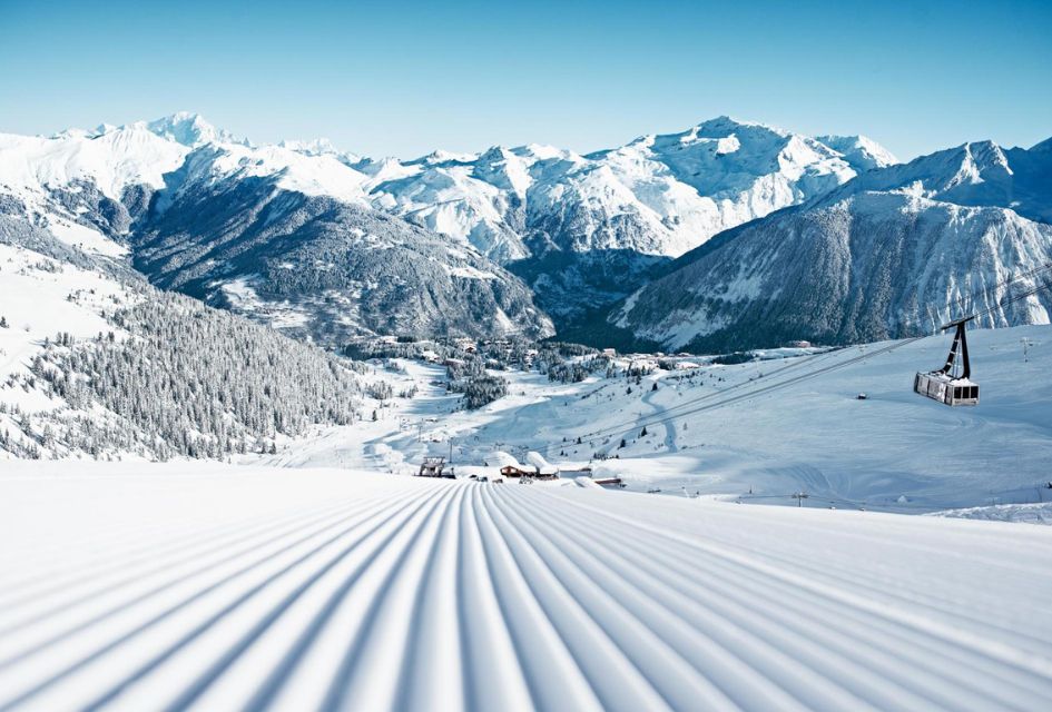 Courchevel 1850. Credit: David Andre Groomed piste of Courchevel 1850, with cable car to the right and the village and mountains in the distance.