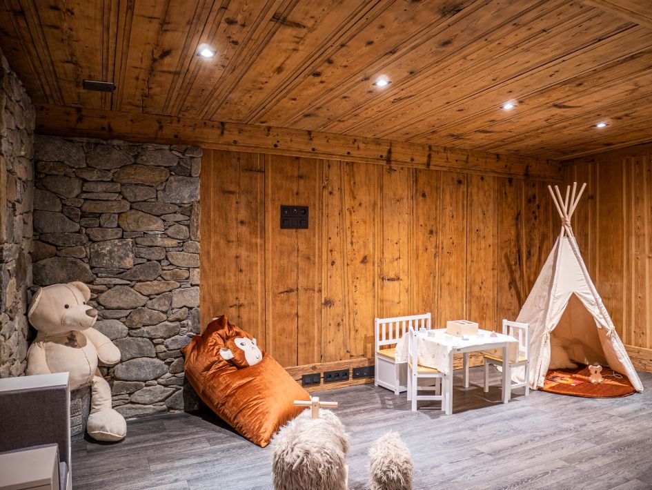 Children's play room with cuddly teddies, cushions, a mini table and chairs and a teepee. Incredible chalet for ski holiday with childcare.