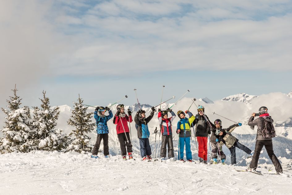 Skier taking a picture of a family ski lesson in Chamonix with snow covered mountains in the background.
