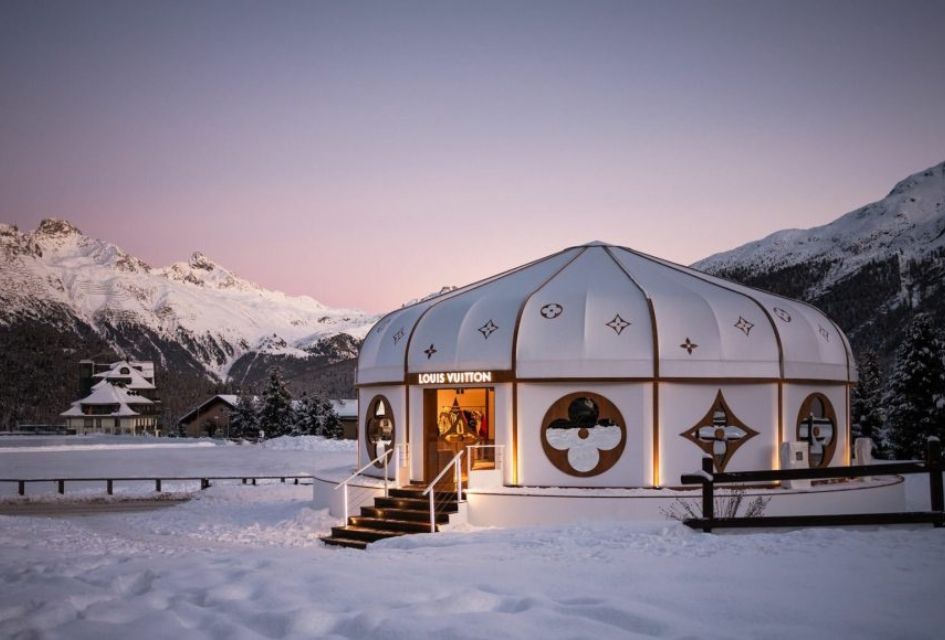 Louis Vuitton, St Moritz The Louis Vuitton yurt pop-up in St Moritz by the lake at dusk, with pink skies above the mountains in the distance.