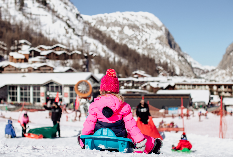 Kindergarten. Credit: Anna Cantu via Val d'Isère Tourism A child enjoying a toboggan ride with mountains and the bottom of the slopes before her in Val d'Isère.