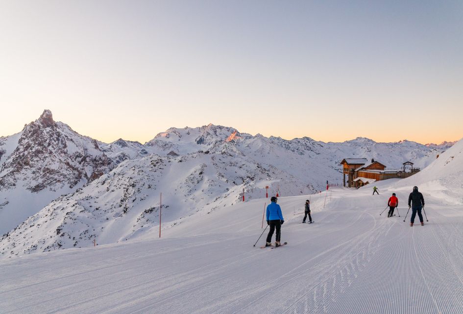 First track experience in Méribel with skiers on a freshly groomed piste and pink glow on the moutnains 