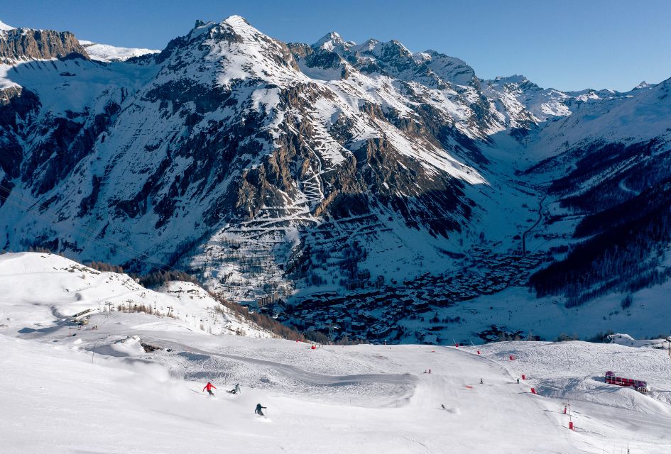 Val d'Isère - Credit: Val d'Isère Tourism, Tristan Shu Mountain peaks of Val d'Isere and a wide open ski slope with a couple of skiers skiing down