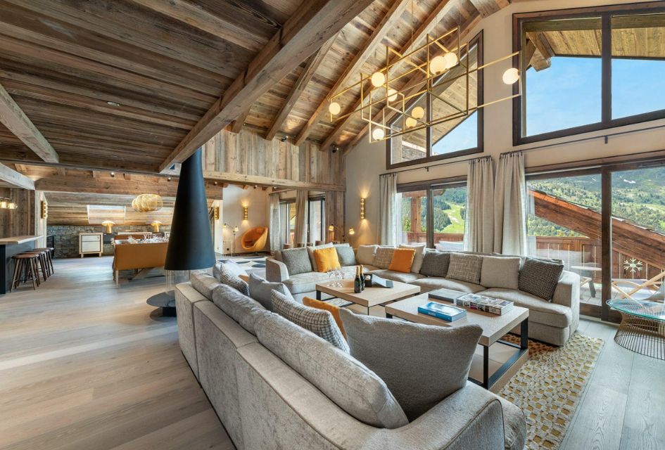 Apartment Village de L’Orée 405, Méribel Incredible, double height, open-plan living area with vaulted ceilings and floor-to-ceiling windows, fitted with lucious sofa area in Apartment Village de L'Orée.