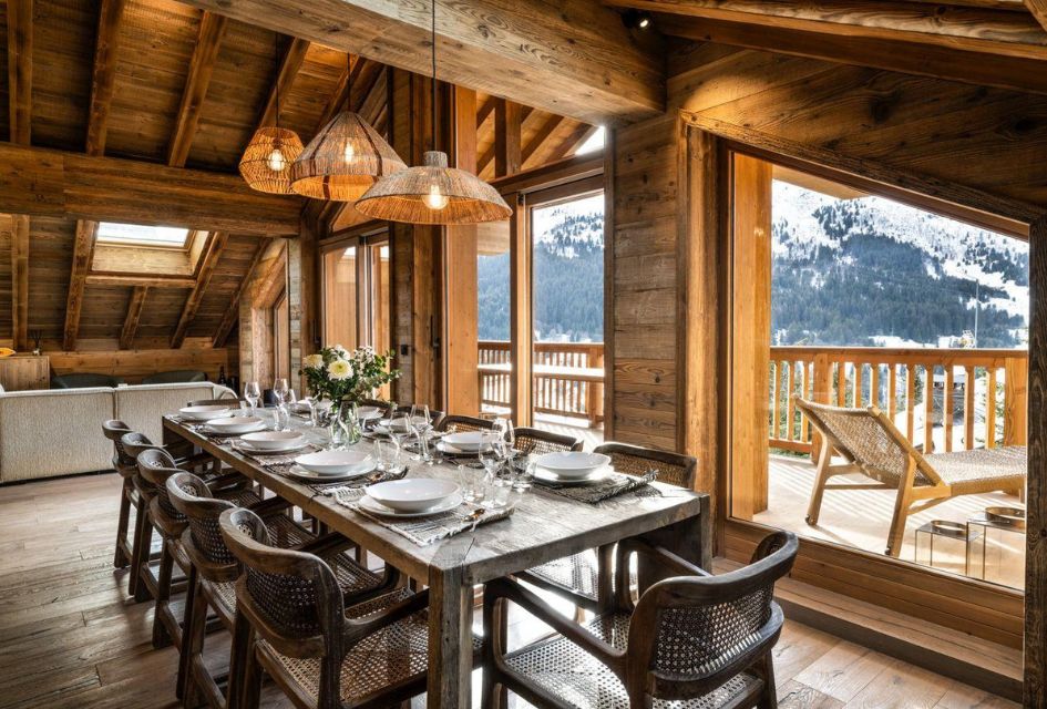Falcon Lodge F21, Méribel Dining with a view from Falcon Lodge F21. Defining alpine beams surround the open plan living space, opening out for large floor-to-ceiling-windows to expose plenty of natural light and mountain views. The table is beautifully decorated, ready and awaiting your group to indulge in the creations of your nominated chef.