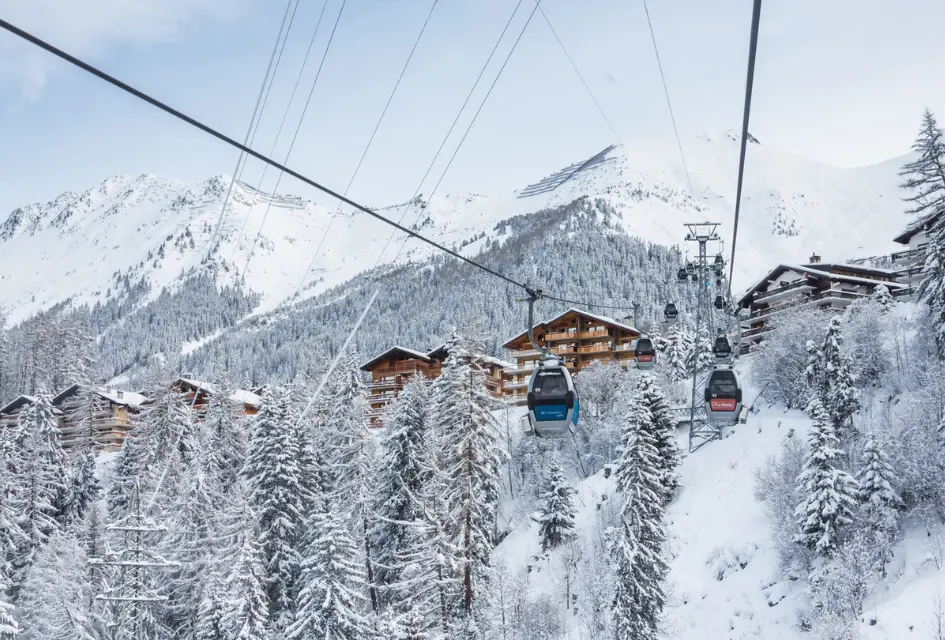 Châble-Verbier. © Verbier 4Vallées Tourism Office Châble-Verbier, cable car through the snowy trees with apartments and chalets in the background.