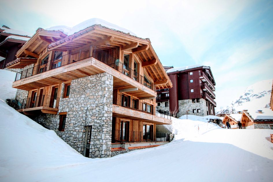 Exterior shot of Chalet La Tene, looking up the relatively flat lower section of the red Santons piste, which winds its way between the chalet buildings.