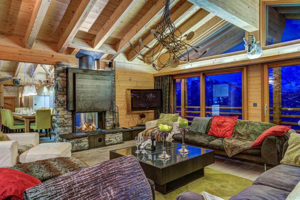 Chalet Auriane, La Tzoumaz A vibrant living area, floor-to-ceiling windows frame the valley for guests to enjoy as they cosy up beside the dual aspect fireplace.