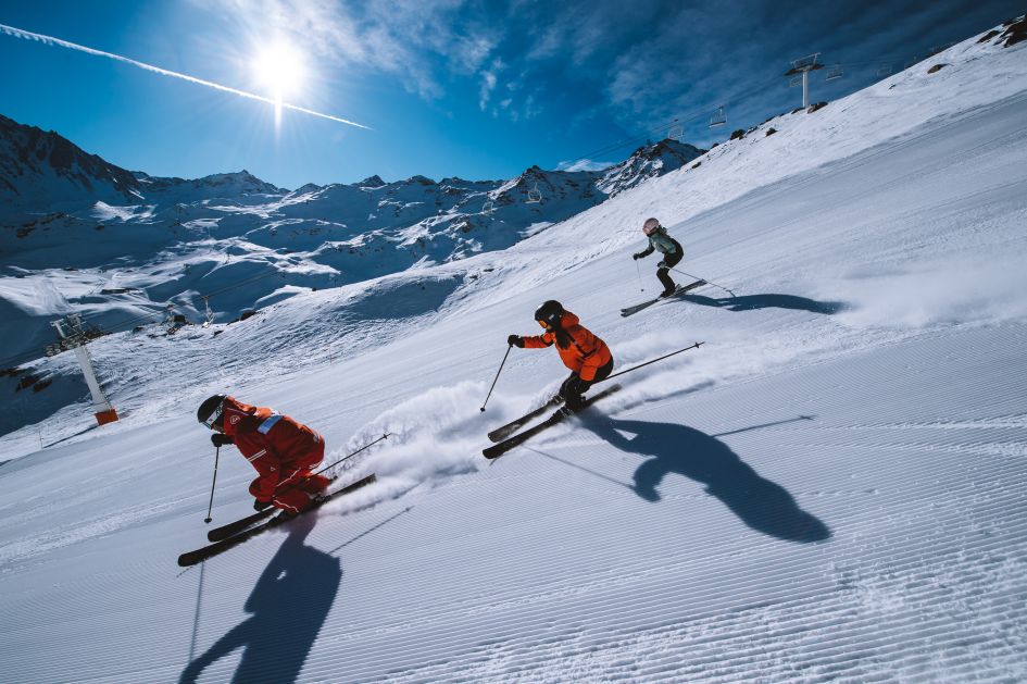 Three skiers on the slopes of Val Thorens on a sunny day.