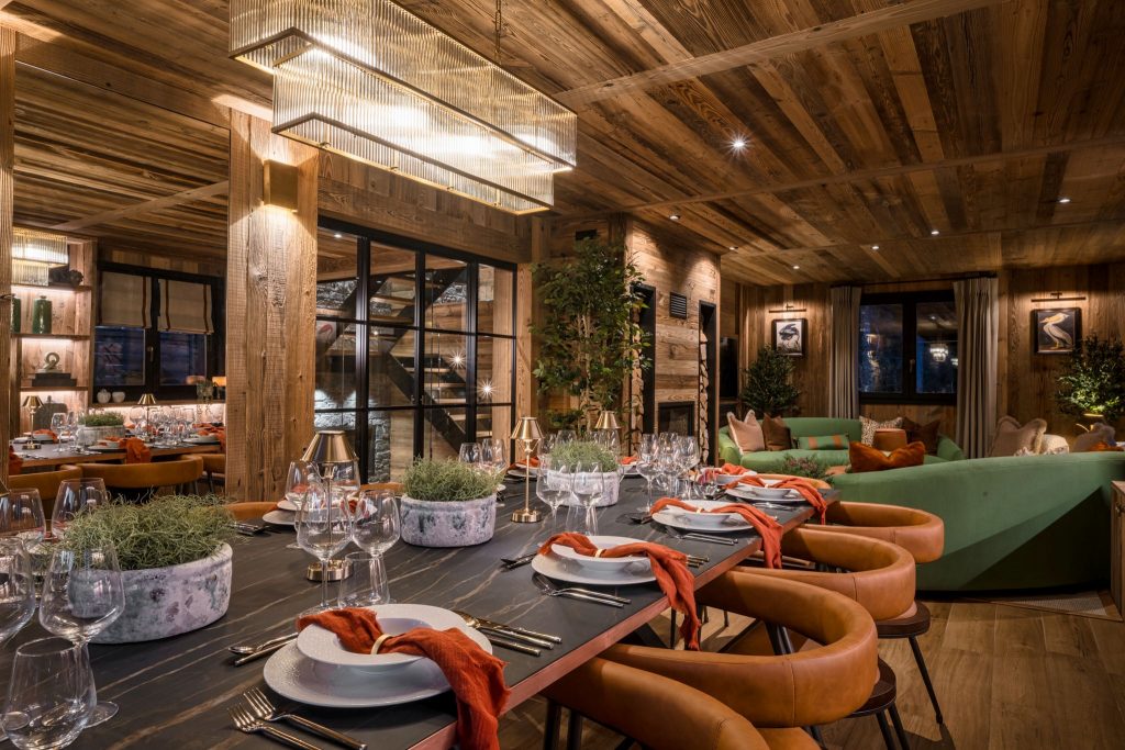 The Bungo, Morzine An upscale, rustic-modern dining and living area in The Bungo. A spacious dining table allows for fine dining, contemporary sofas lie in the background.